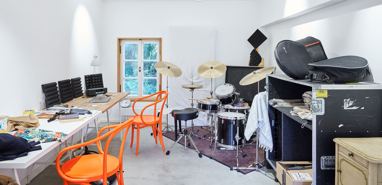 View of a study with tables on the left and a drum kit on the right