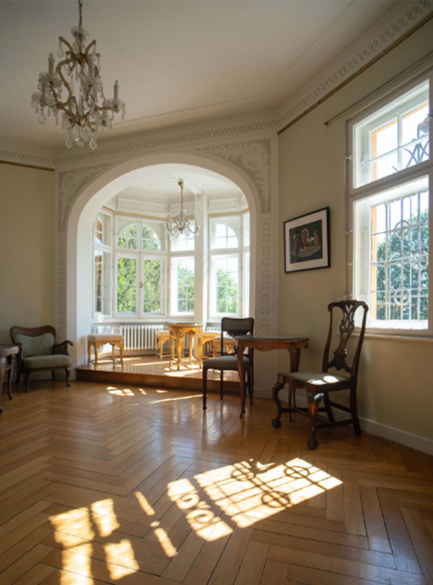 The light-flooded bay window room in the villa with herringbone parquet flooring in the foreground