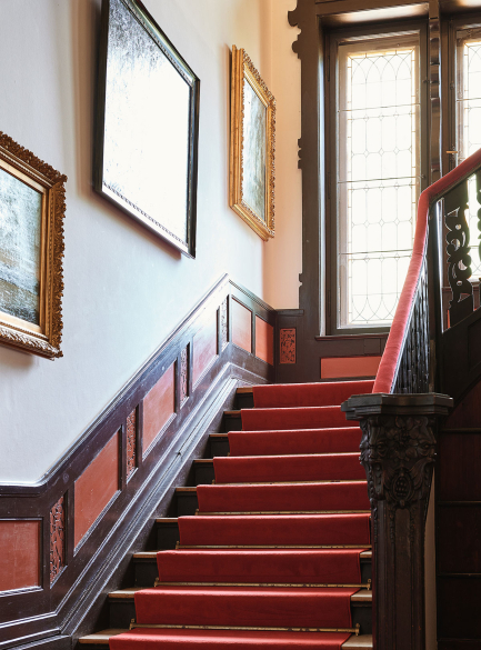 Staircase to the upper floor with wooden steps and paintings on the wall